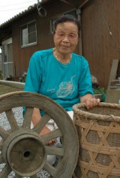 「この車輪と竹かごは養蚕をしていた証し」と話す立川さん。後ろは蚕室として使った2階屋