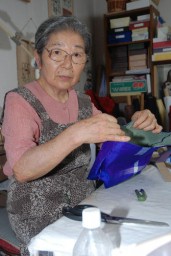 作業部屋で銘仙素材の小物入れを作る山崎さん