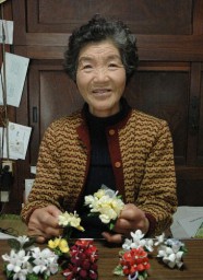 繭で作ったコサージュを手に「やっぱり自分で蚕を飼わないと」と話す藤巻さん