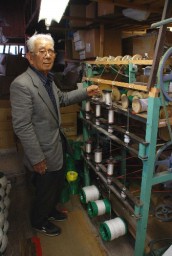 店舗裏の工場で使用する特注器械の前に立つ贄田さん