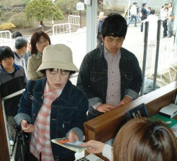 事務所でしおりや入場券を受け取る来場者