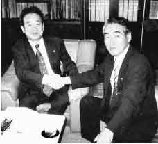 横浜市中区役所で屋代区長と握手する熊川村長(右)
