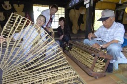 わらで編んだ「まぶし」を手に取って見る来場者