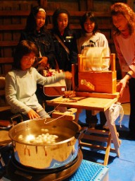 慣れない手つきで座繰りを体験する小学生ら