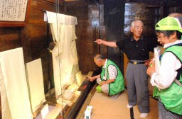 登坂代表(中央)の説明を聞きながら天蚕製品を見るガイド